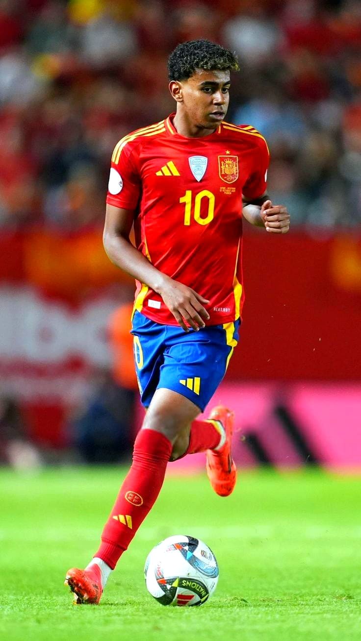 A soccer player in a red and yellow Spain jersey with number 10 dribbles a ball on the field during a match. The stadium background is blurred, highlighting the player’s focus and movement—perfect moments for fans who want to catch all the action live when they purchase IPTV.
