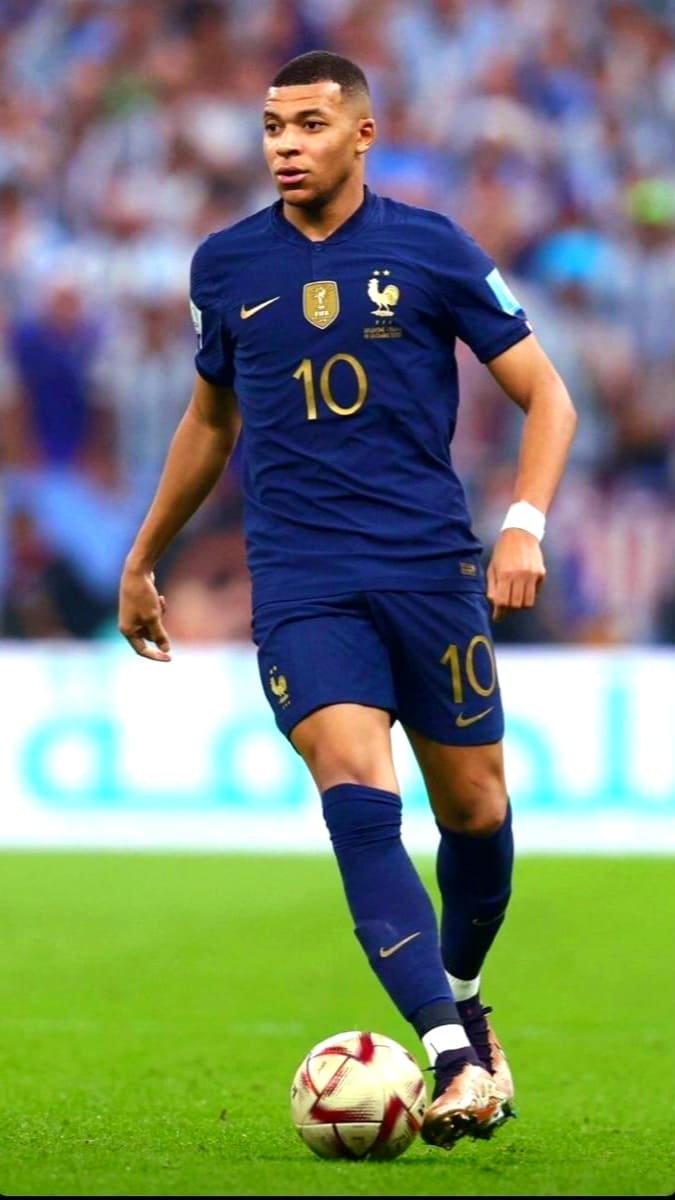 A soccer player in a blue France jersey with number 10 controls a ball on the field during a match, with a blurred crowd in the background—a scene you can experience live from anywhere when you purchase IPTV.