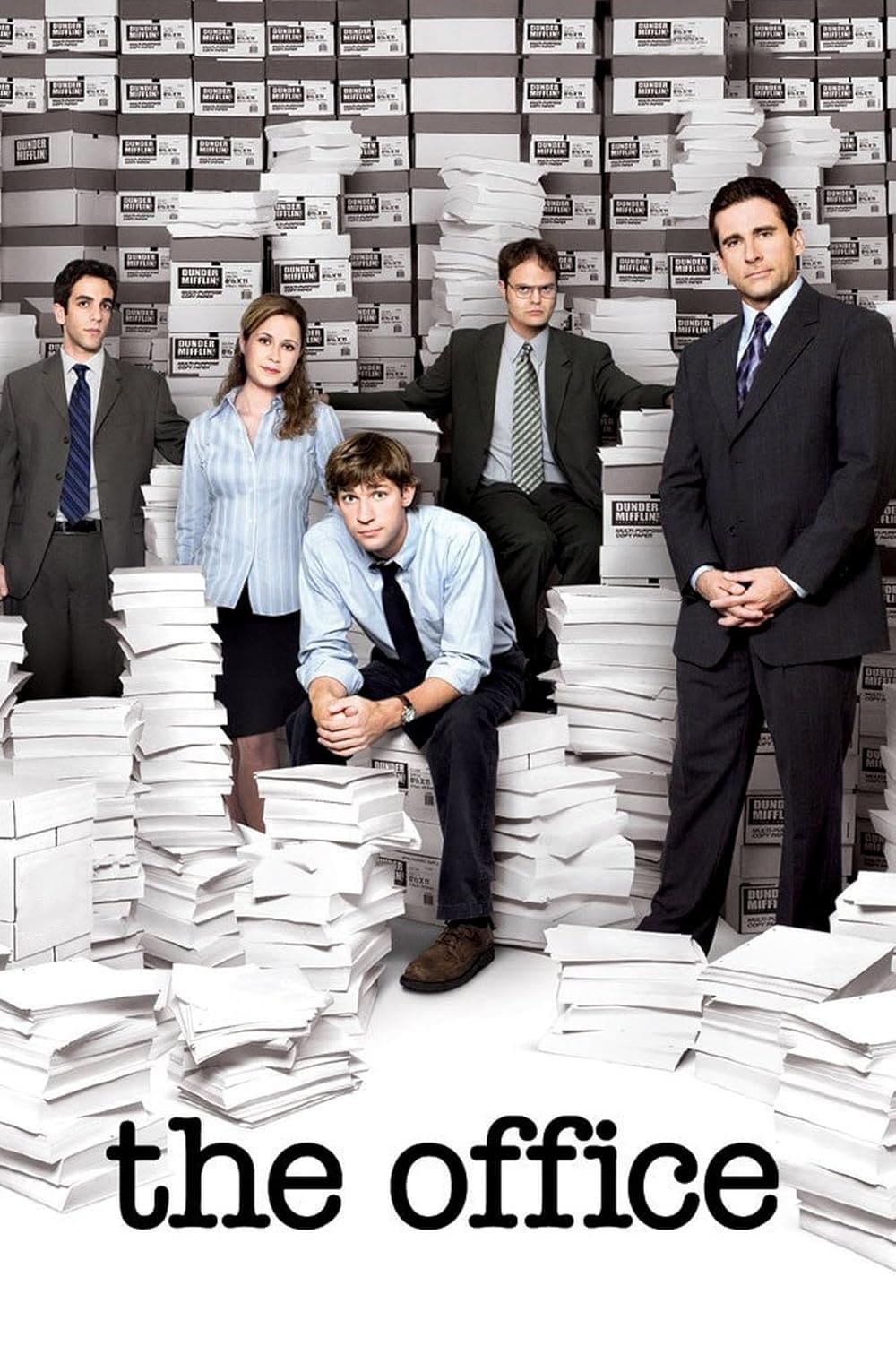 Five people in office attire pose among tall stacks of paper and boxes labeled “copy paper.” The title “the office” is at the bottom of the image in bold, black letters—perfect for fans looking to purchase IPTV and stream their favorite workplace comedy anytime.