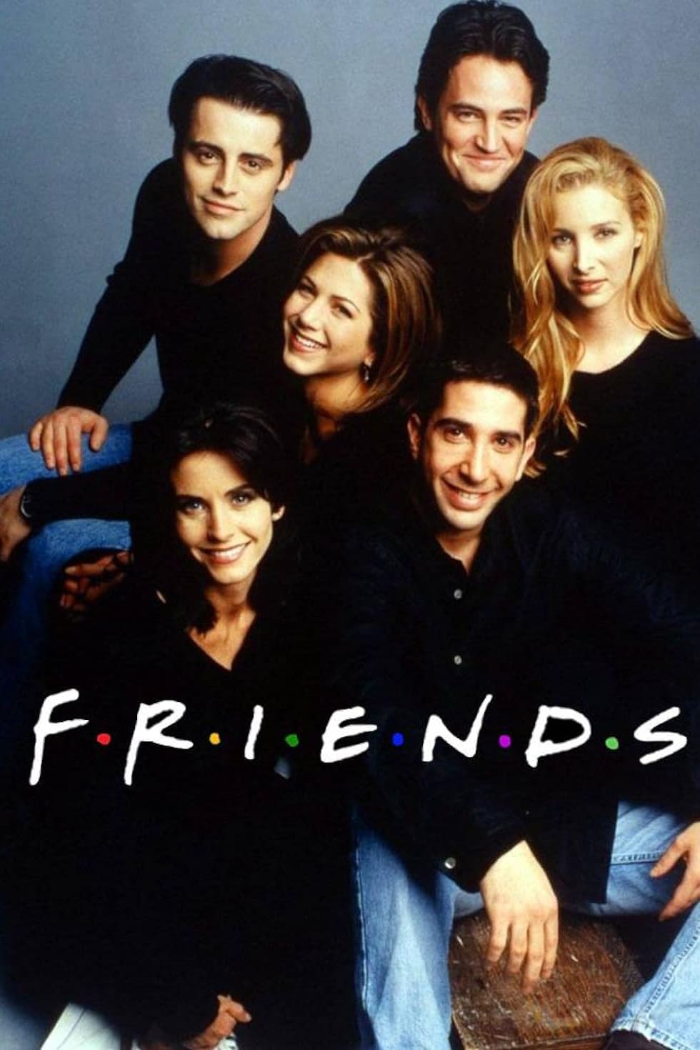 Six people pose closely together, smiling, against a plain background. The word FRIENDS is written across the bottom in white letters with colored dots between each letter, evoking the feeling of gathering to watch your favorite shows—just like you can when you purchase IPTV.