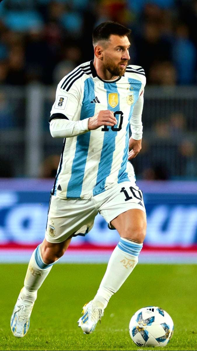 A soccer player in Argentina’s national team uniform runs on the field while controlling a ball during a match. He wears a white and light blue striped jersey with the number 10, as the vibrant energy of the game unfolds before a blurred crowd. For fans eager to catch all the live action, it’s never been easier—simply purchase IPTV to watch every thrilling moment from anywhere.